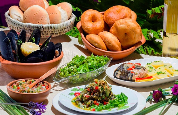 Mesa con platos típicos de la Costa Araucanía: choros al vapor, merluza frita, pebre, sopaipillas, pan amasado y ensalada de arvejas.